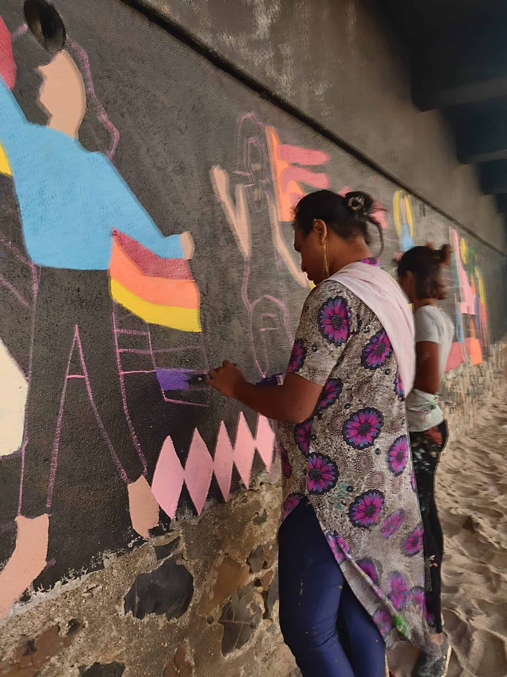 Aravanit Art Members paint over a black wall in public. 