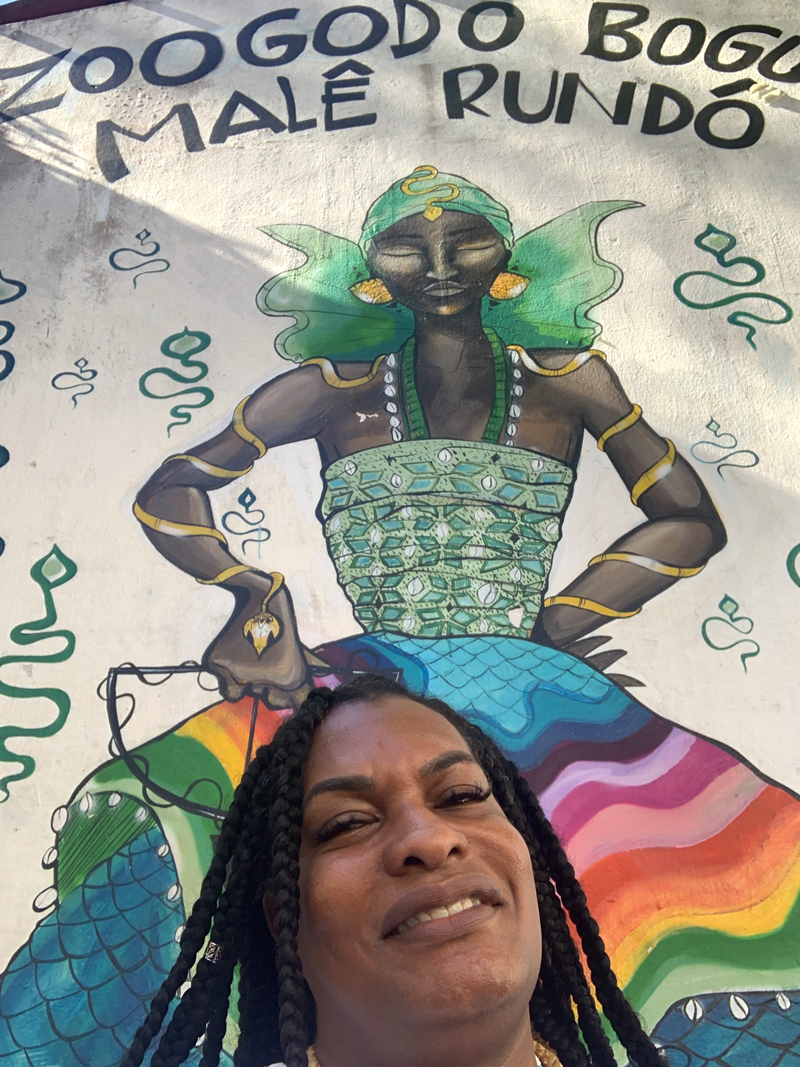 Imara Jones, Black trans woman and CEO of Translash Media in front of a mural in Salvador da Bahia.