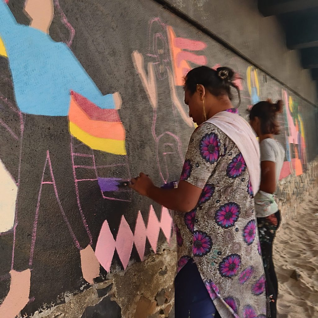 Aravanit Art Members paint over a black wall in public. 