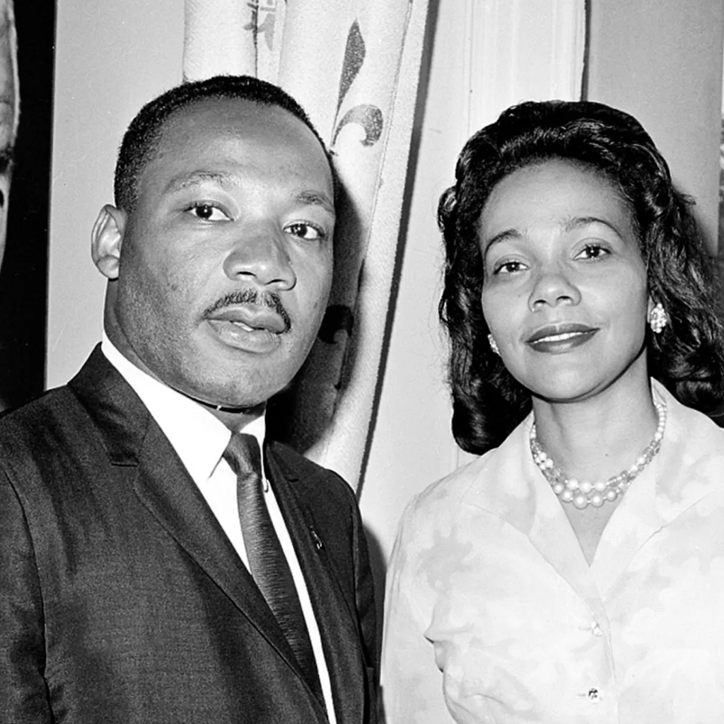 
Alternative text for the image: "A black and white portrait of Dr. Martin Luther King Jr. and Coretta Scott King, posing side by side. Dr. King is on the left, dressed in a suit and tie, while Coretta Scott King is on the right, adorned with a pearl necklace and wearing a light-colored blouse. Both are looking directly at the camera with composed expressions.