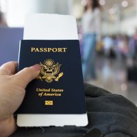 White hand holds an American passport while sitting in an airport terminal
